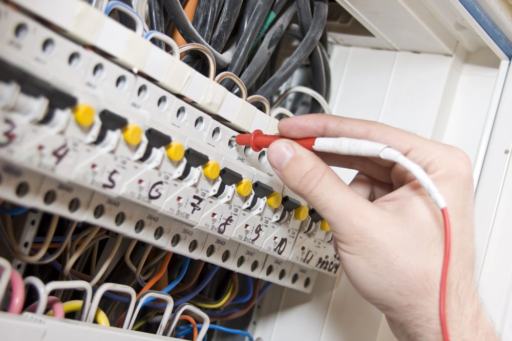 Prueba manual del cableado eléctrico con una sonda roja y blanca dentro de un panel de interruptores.