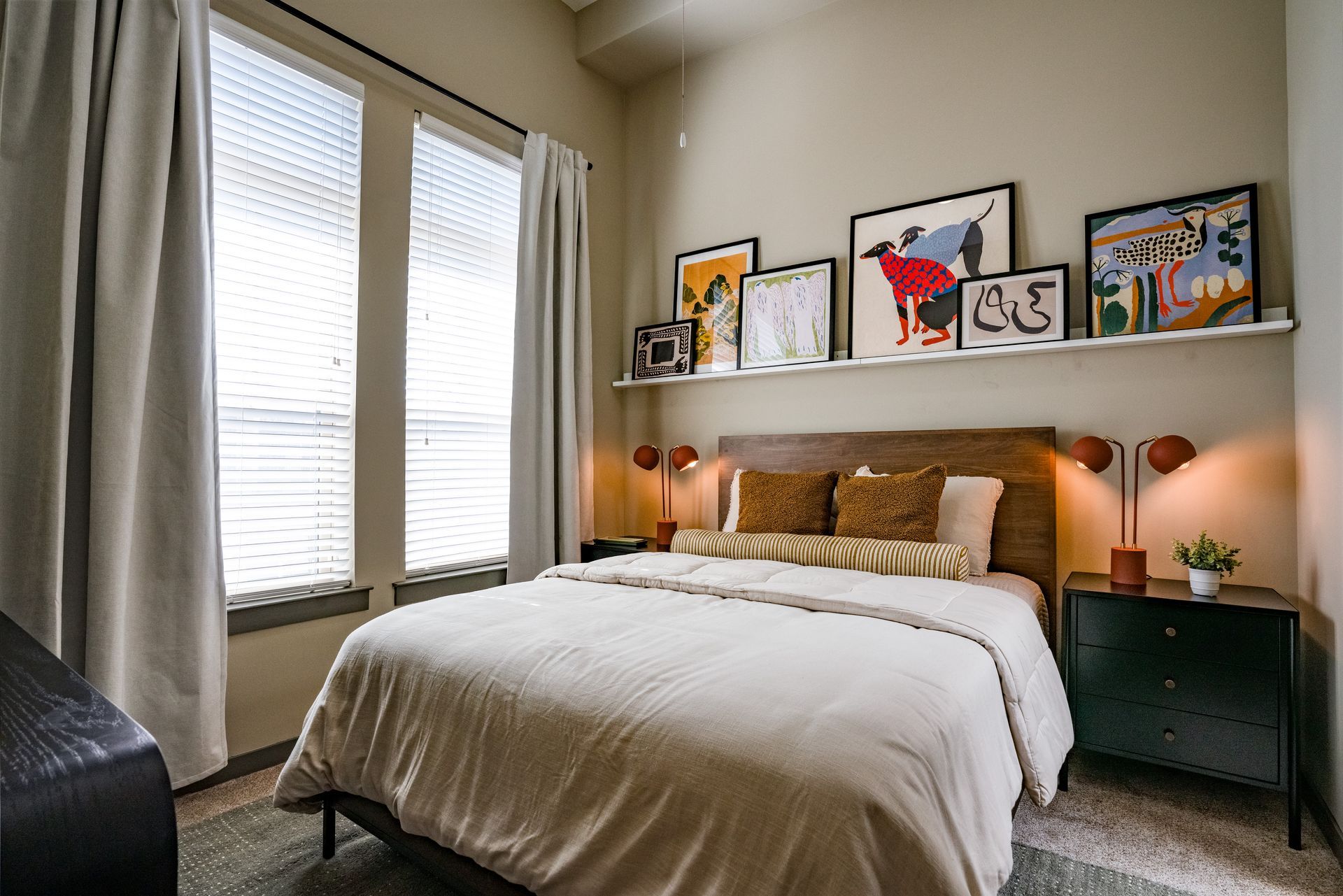 Bedroom with a bed, nightstand, and artwork above it. A window is on the left, and the walls are painted a light tan color.