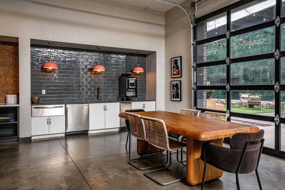 A modern office common area featuring a wooden table with chairs