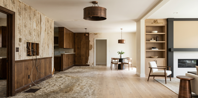 Spacious modern living room with wood floors, built-in shelves, and a fireplace opening to a dining area