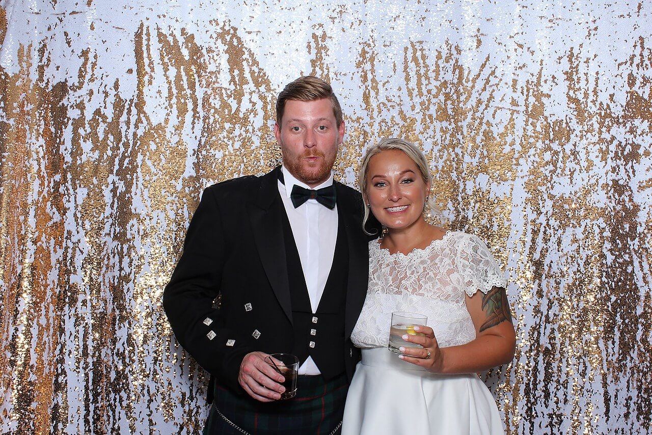 Bride and groom in front of their photo booth rental at their wedding
