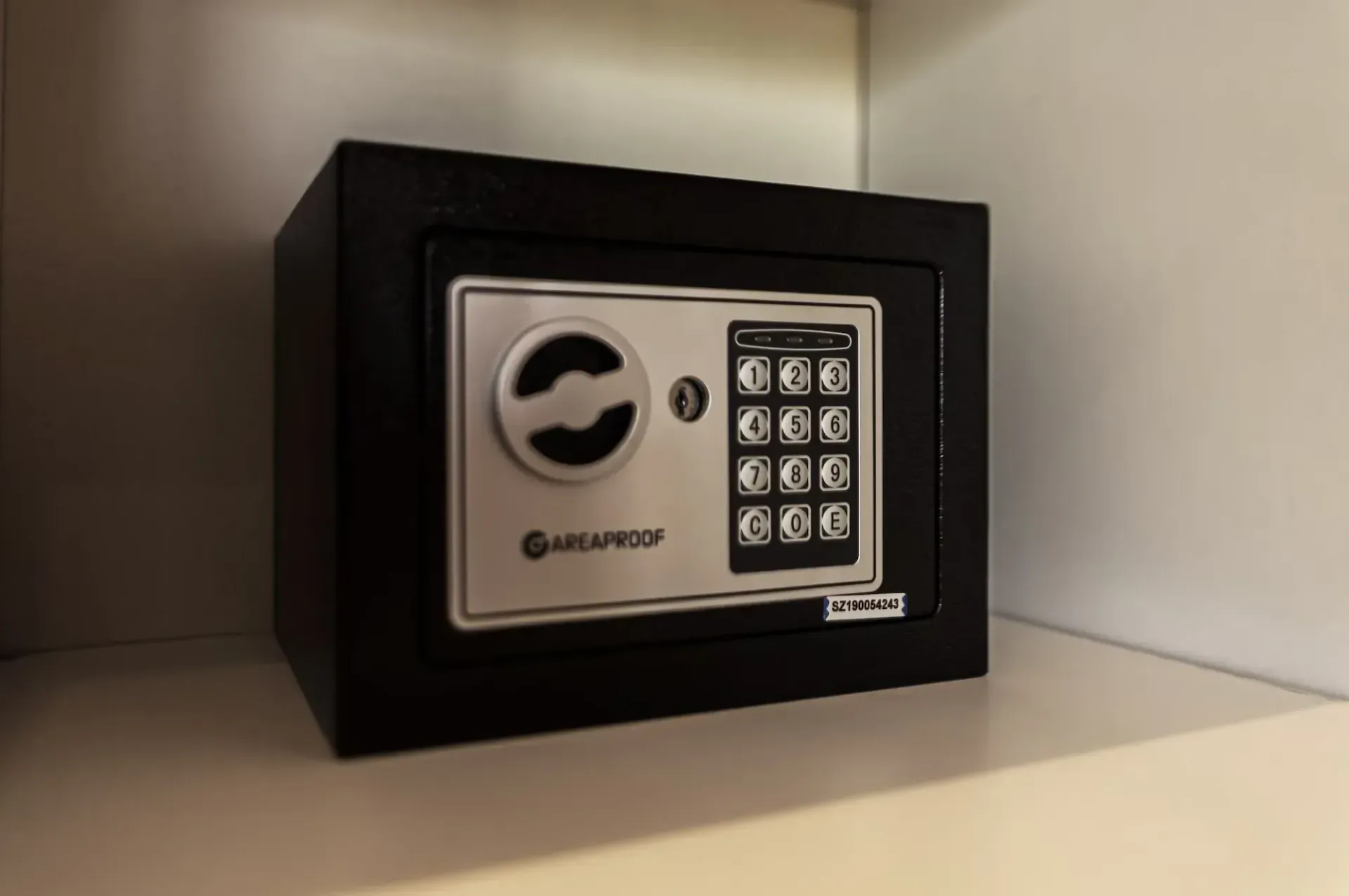 A black and silver safe is sitting on a white shelf.