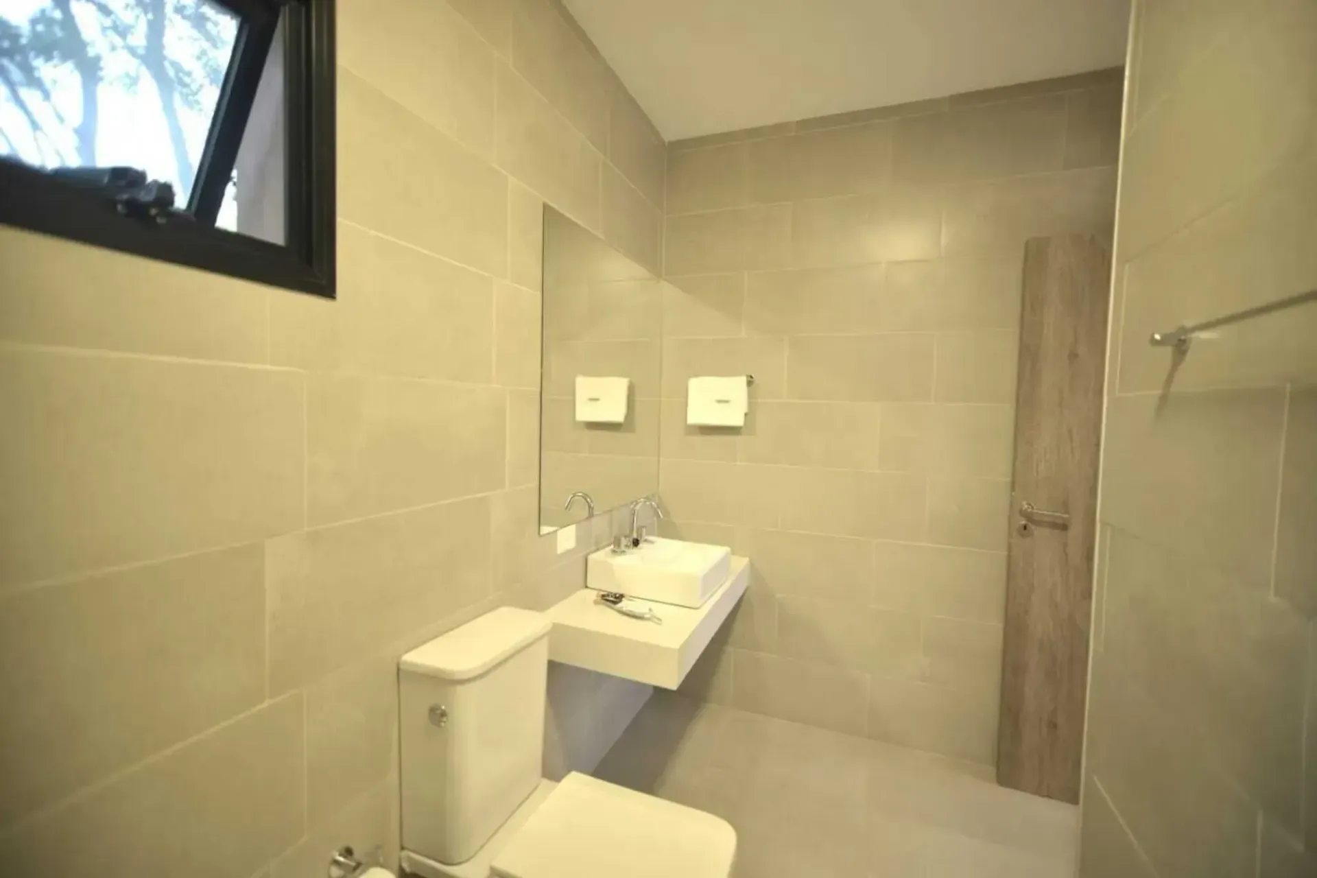 A bathroom with a toilet , sink and mirror.