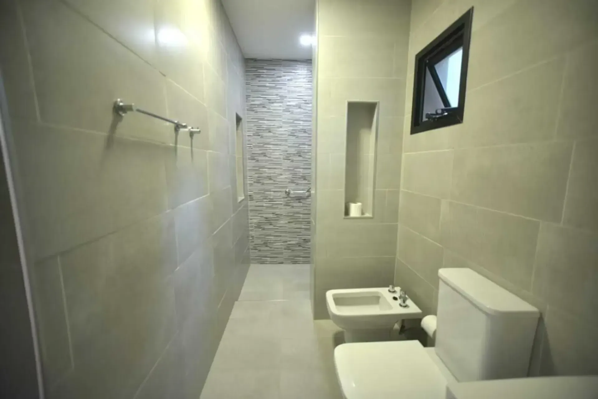 A bathroom with a toilet , bidet and shower.