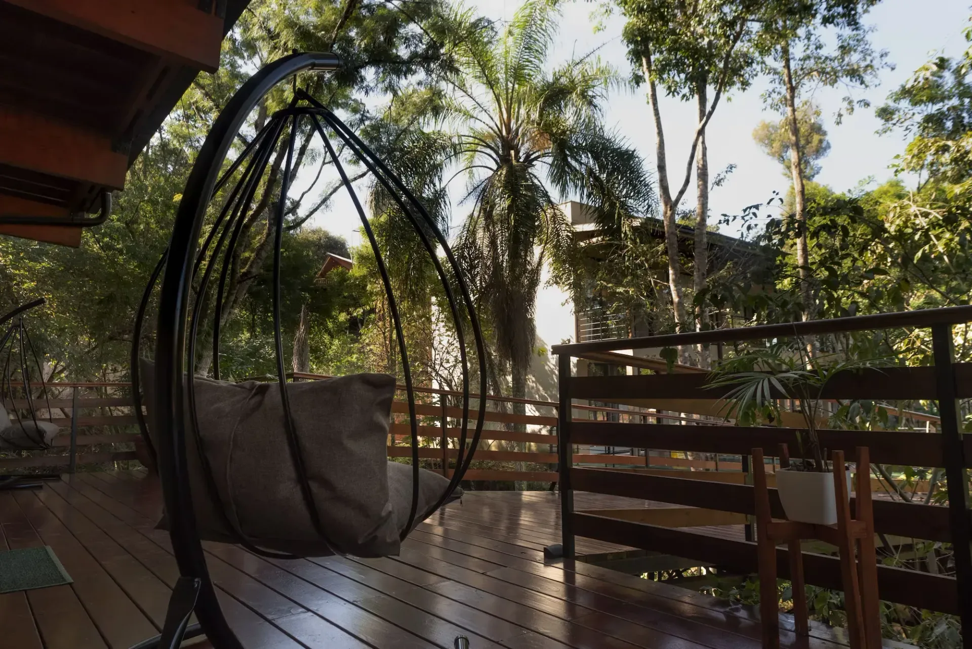 A hanging chair on a wooden deck with trees in the background