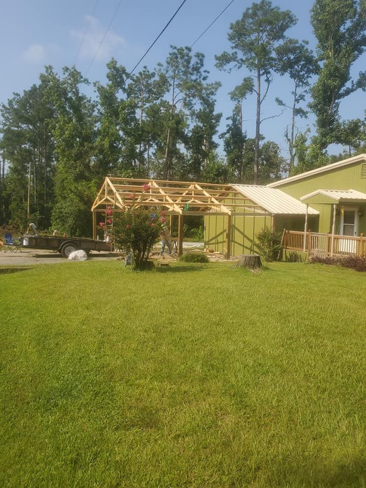 Rural house under construction beside a green lawn and trees on a sunny day