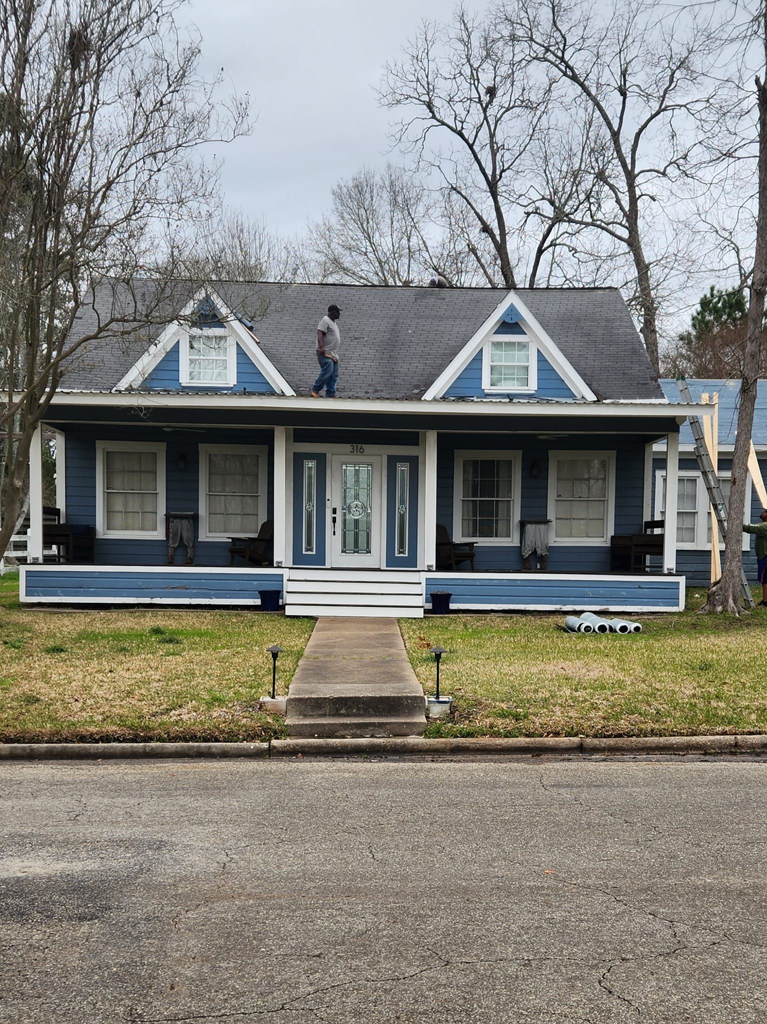 Blue and white Victorian house with a front porch, dormer windows, and a central walkway