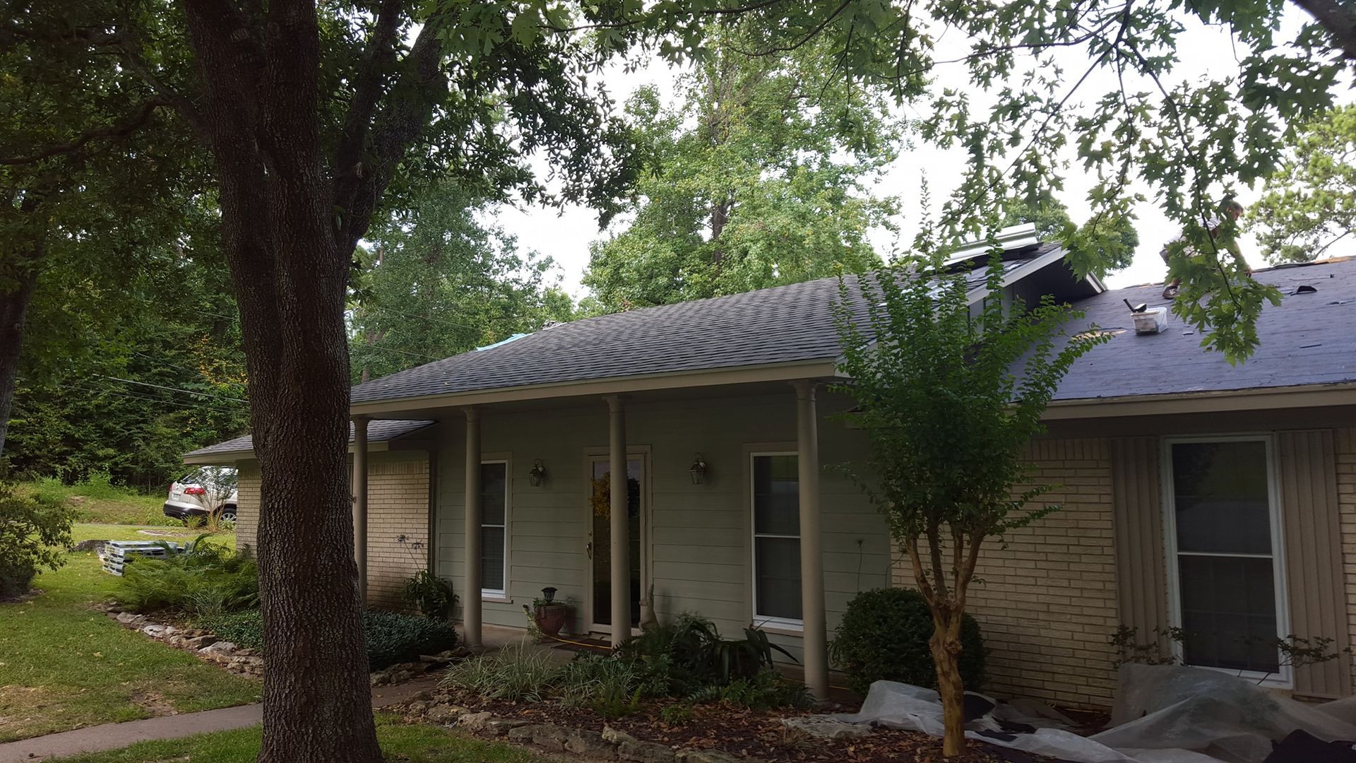 Single-story brick house with a covered porch and trees in the front yard