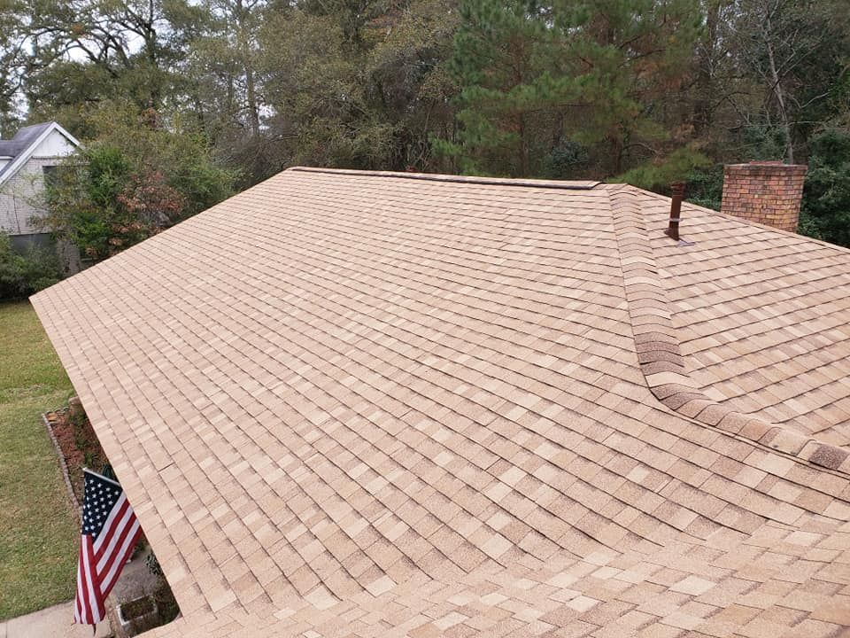 Wide tan shingle roof with a brick chimney and an American flag visible at the lower left.