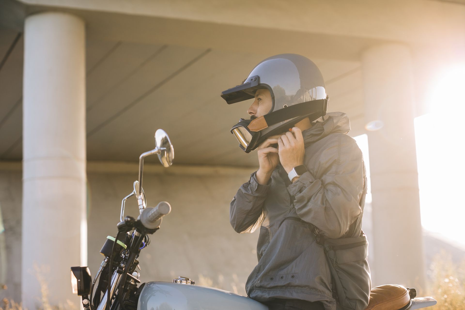 Person putting on a motorcycle helmet while sitting on the motorcycle.