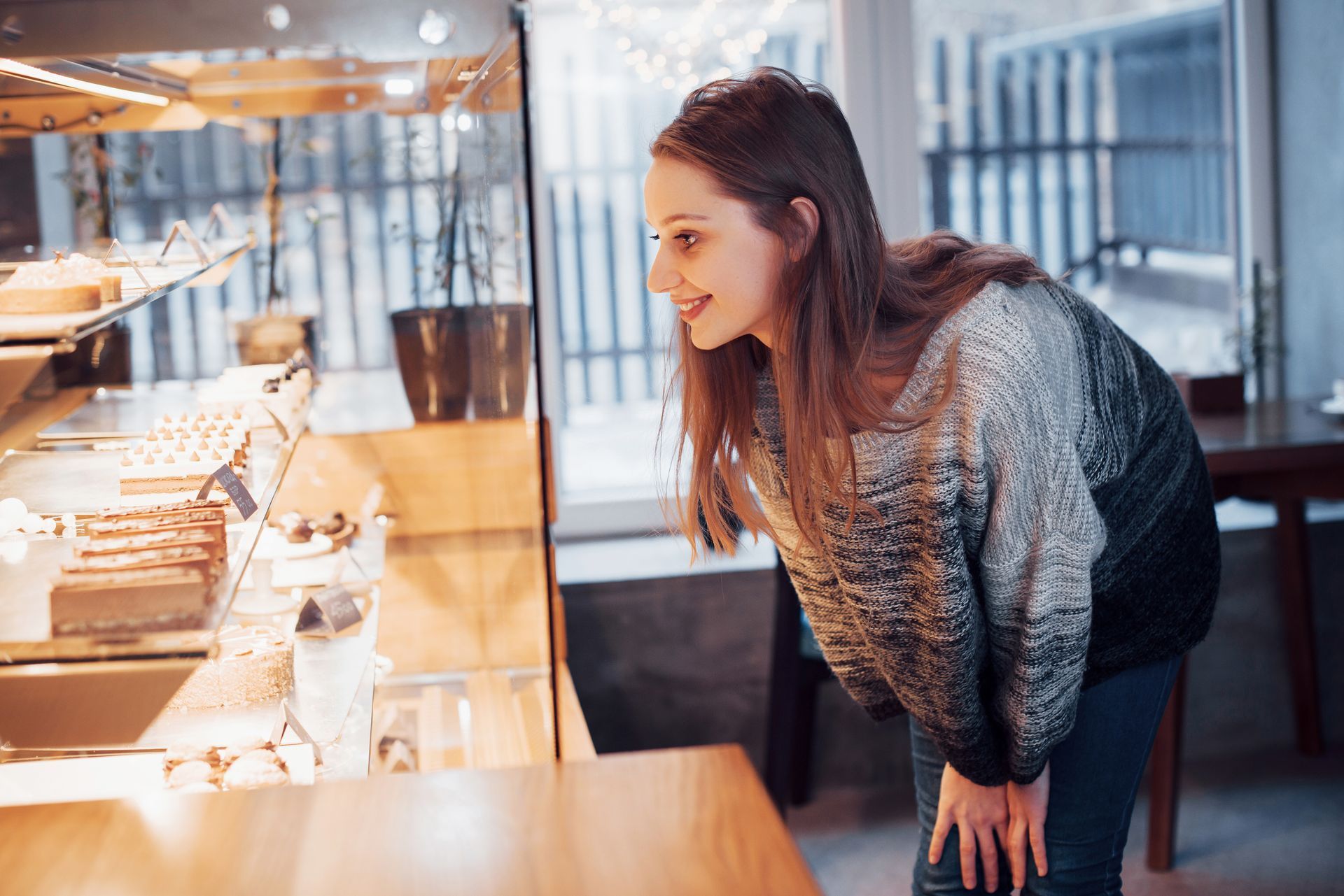 A woman smiles at jewelry in a display case.