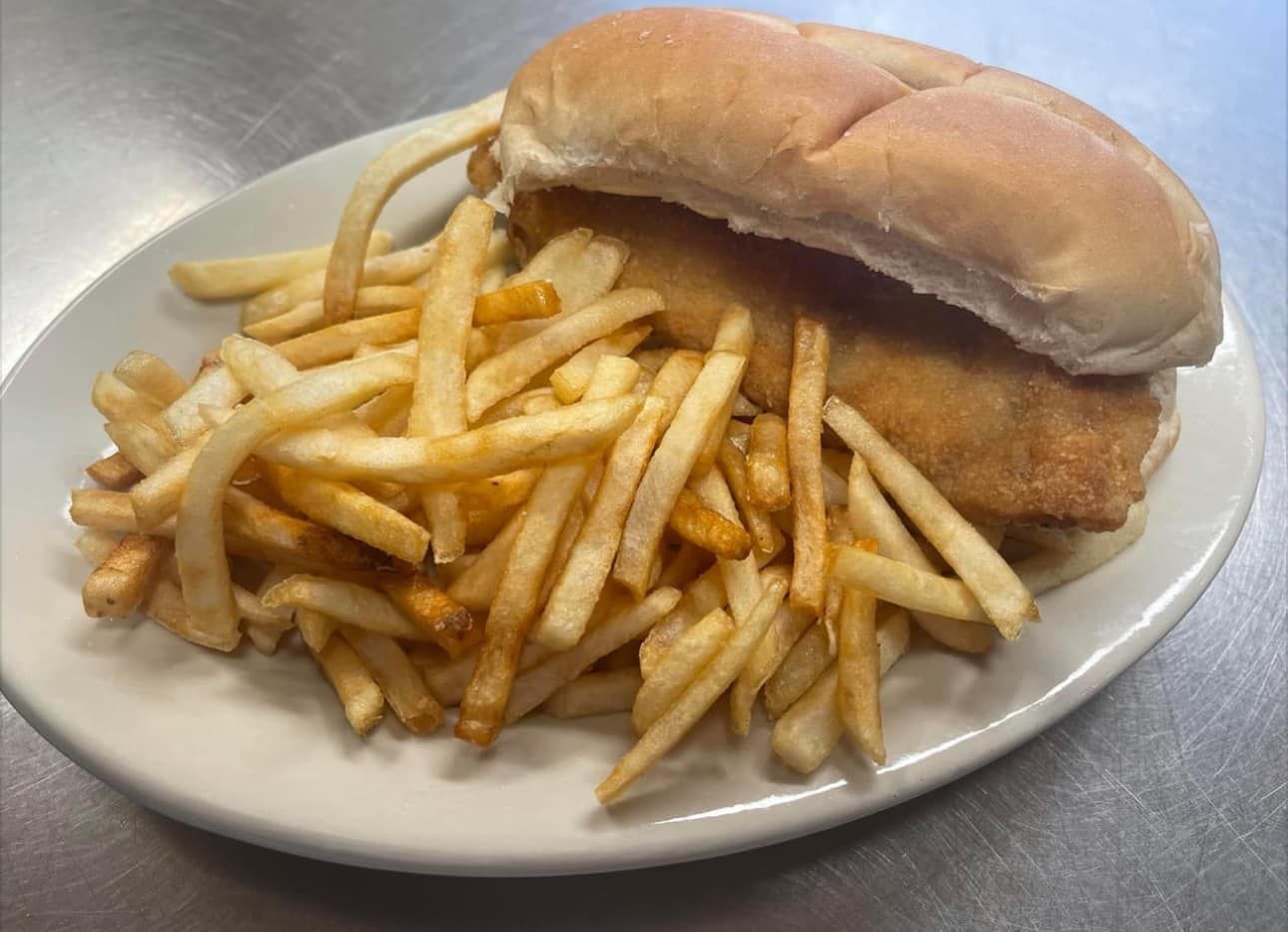 A fish sandwich and french fries on a white plate.