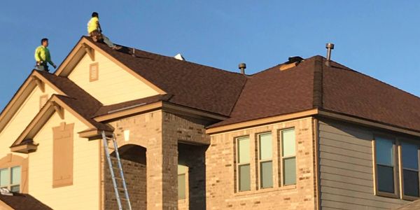 Two men are working on the roof of a house.