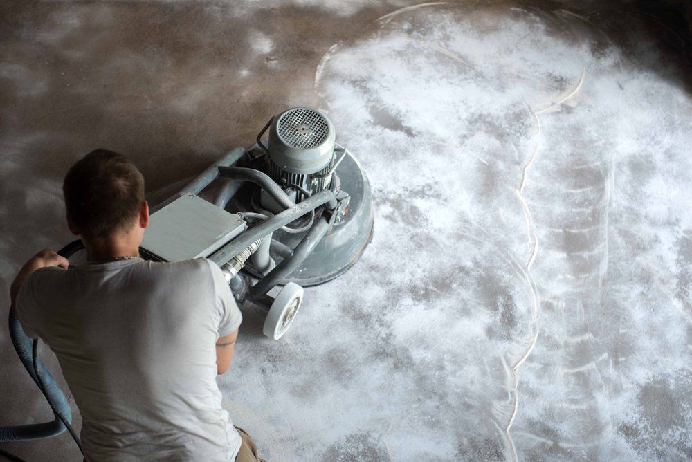 Man Grind the Concrete Surface Before Applying Epoxy Flooring — Demolition Services In Brisbane, QLD