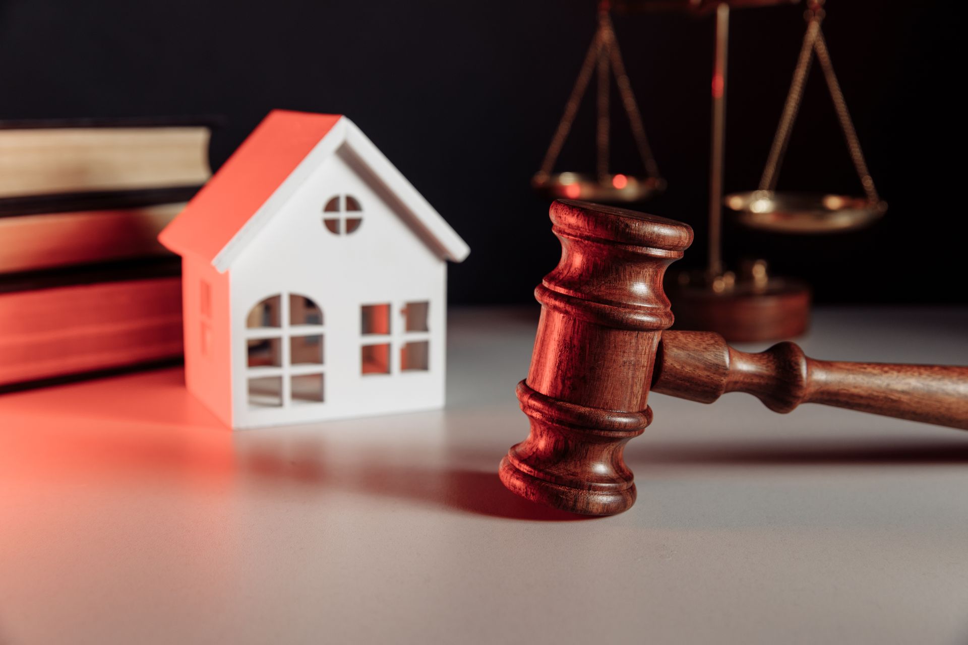 Gavel with a toy house, books, and scales of justice, symbolizing property law.