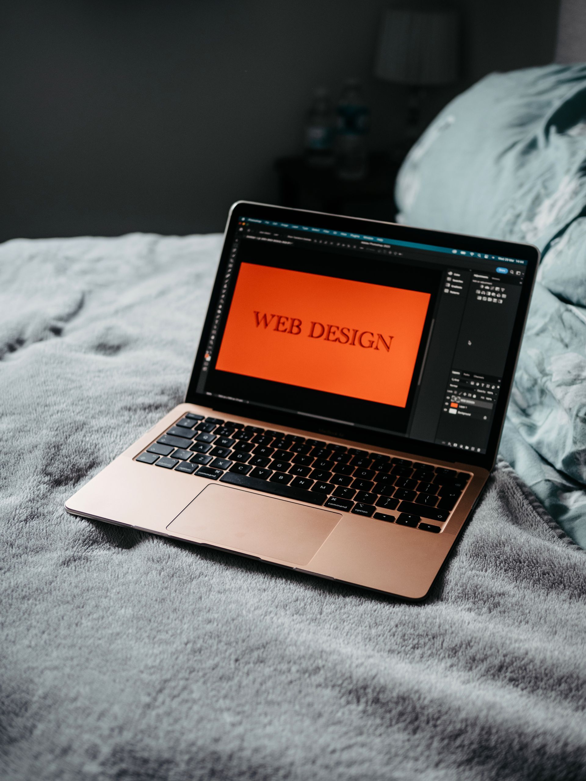 Laptop displaying a web design on an orange screen, resting on a gray blanket