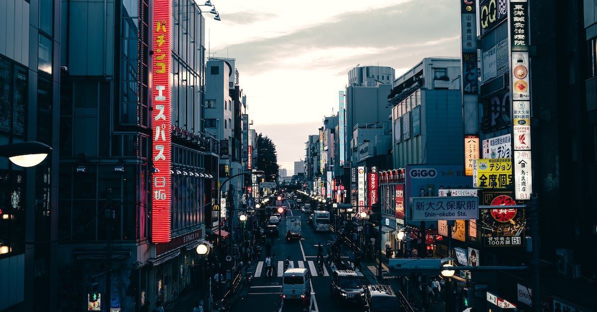 Busy city street lined with neon signs and traffic at dusk between tall buildings