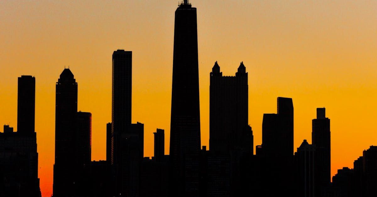 Dark city skyline silhouettes against a bright orange sunset sky