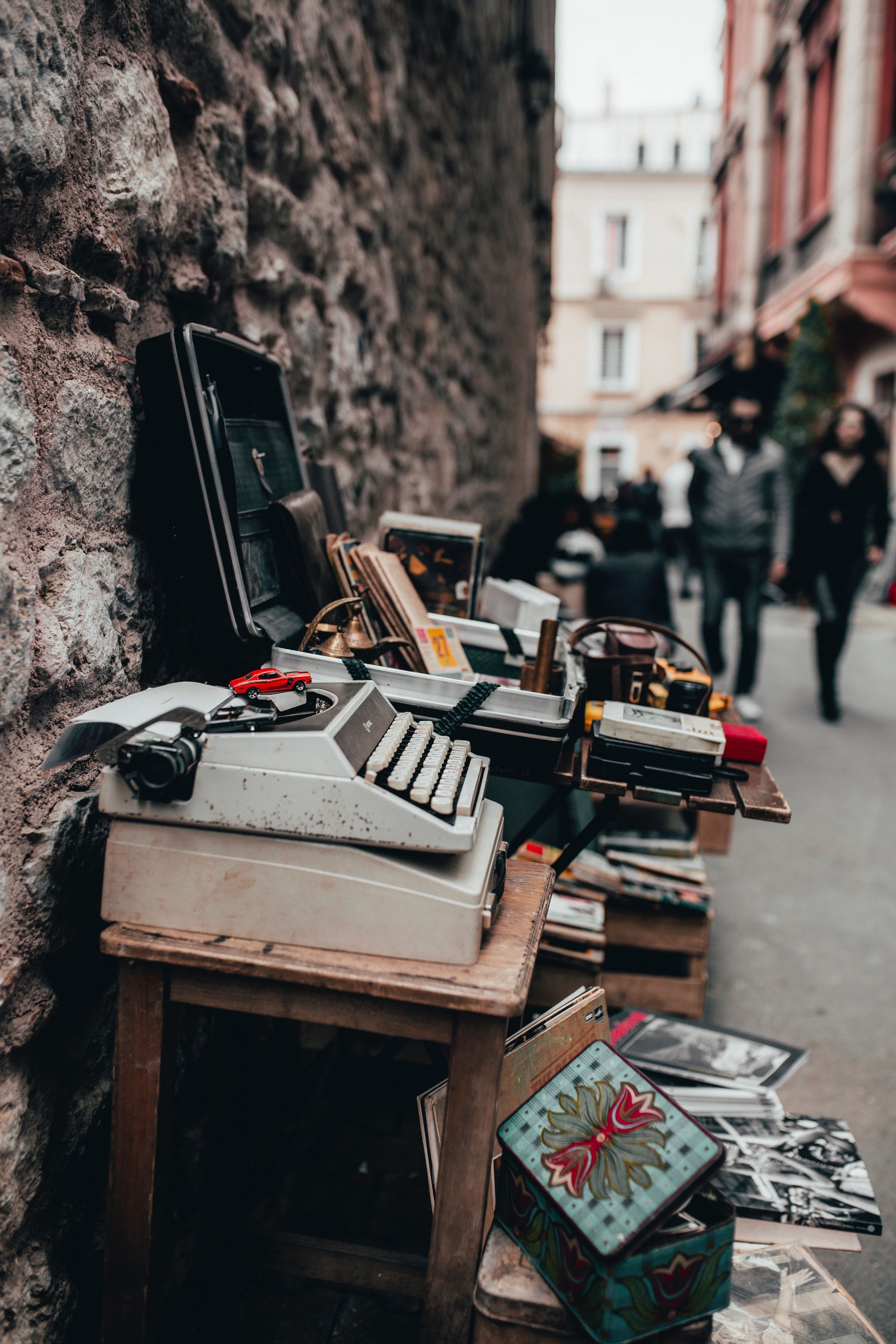 Street market stall with vintage electronics and records along a narrow urban alley