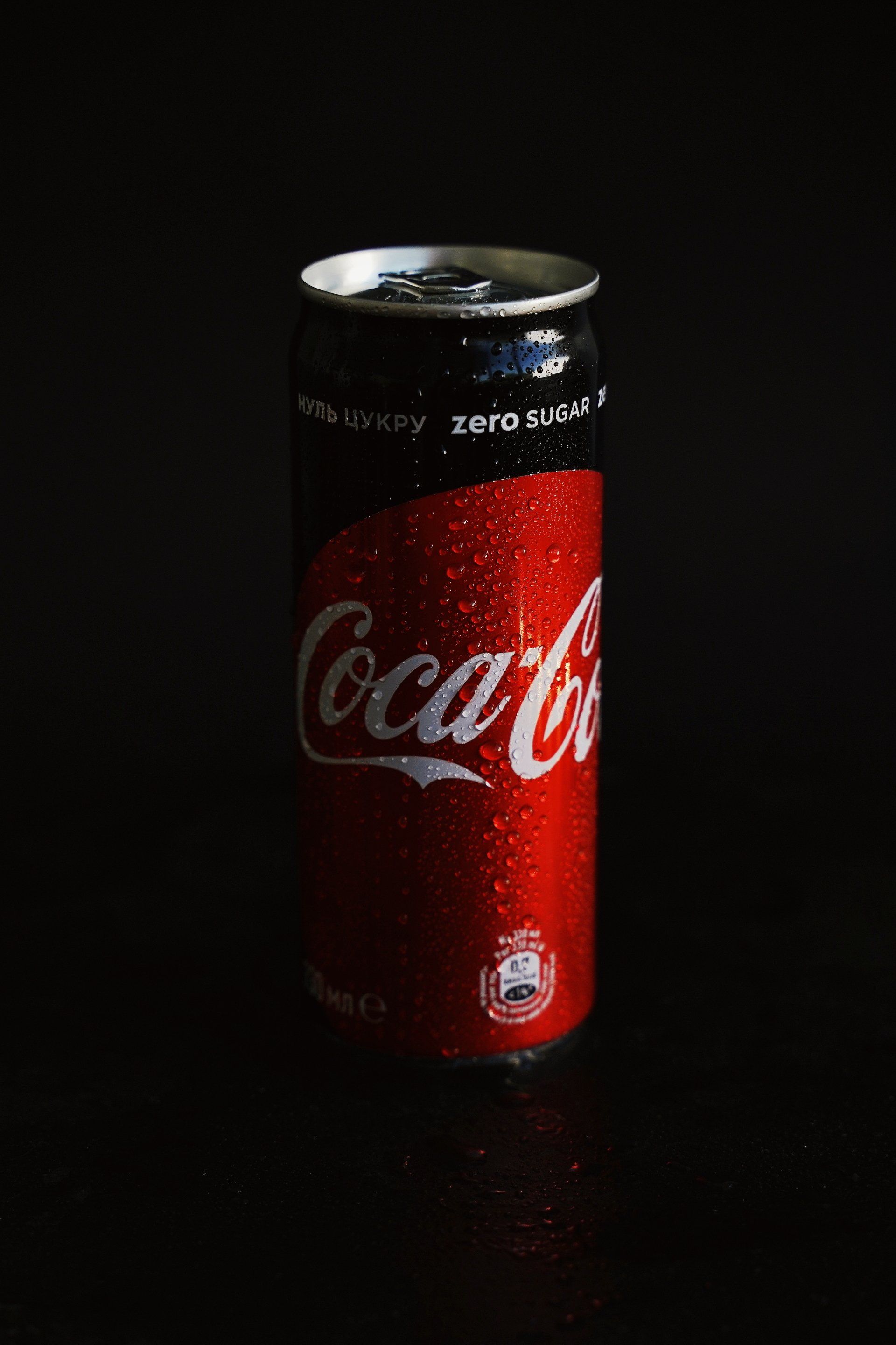 A red Coca-Cola can with condensation against a dark background.