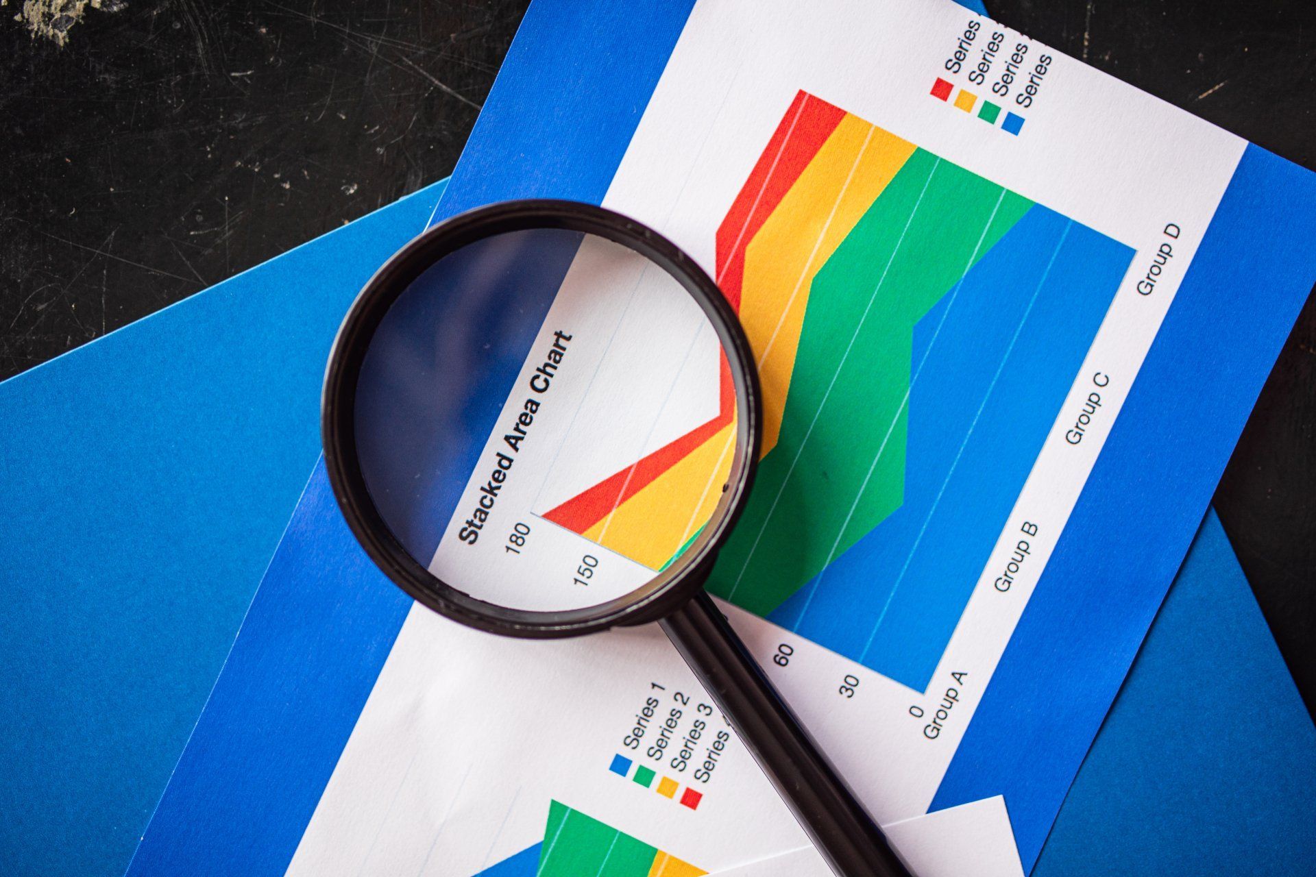 Magnifying glass over colorful charts and graphs on printed reports