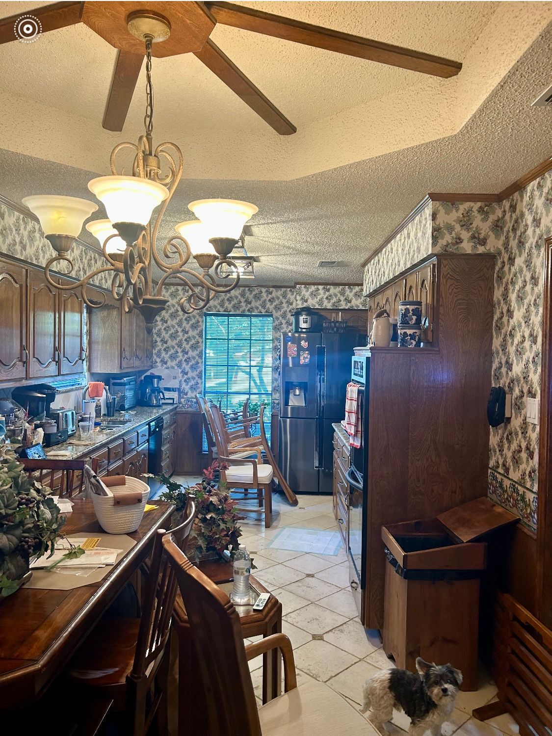 A kitchen with a ceiling fan and a trash can