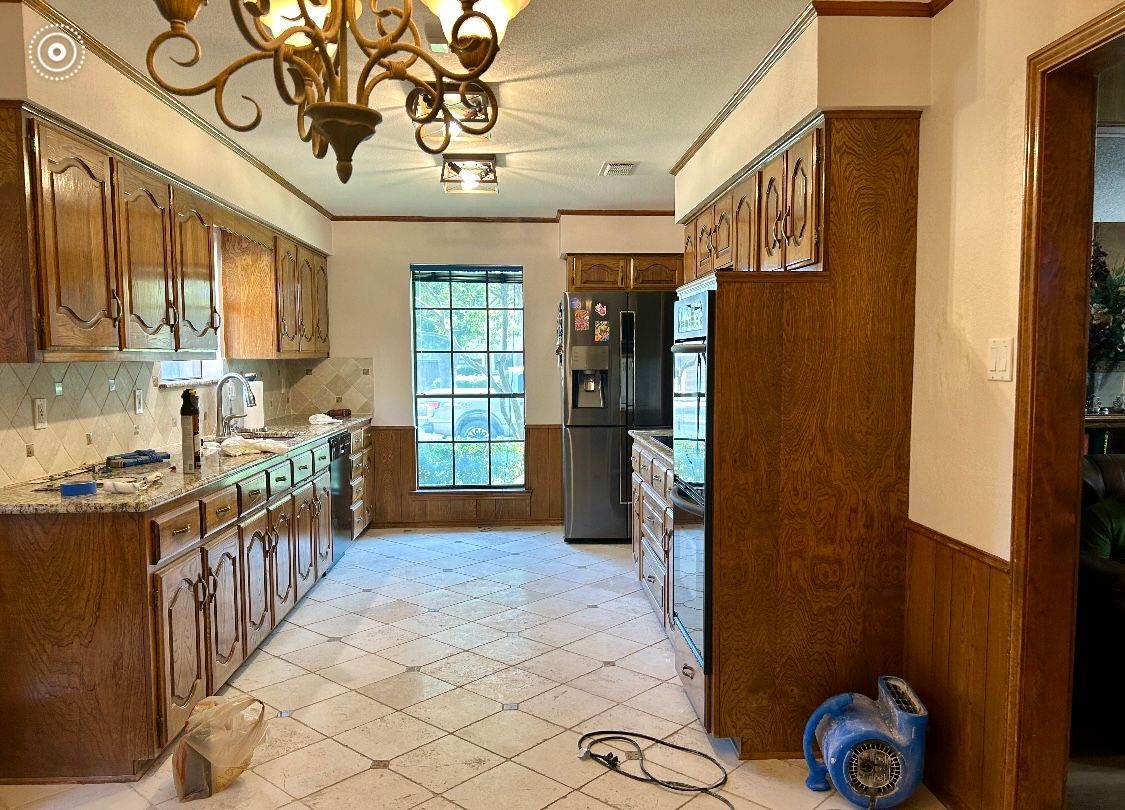 A kitchen with wooden cabinets and a stainless steel refrigerator.