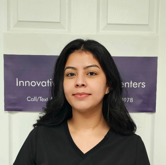Portrait of a woman in black standing before a purple Innovation Centers sign