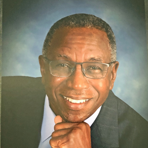 A man wearing glasses and a suit smiles for the camera