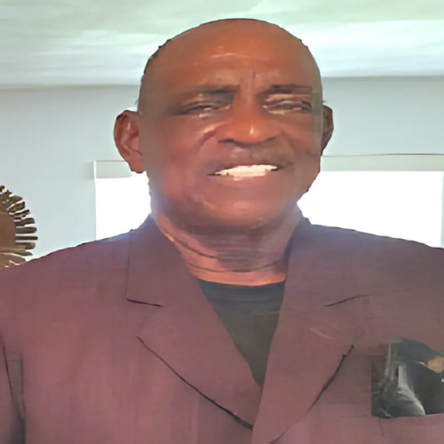 A man in a purple suit is smiling for the camera