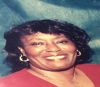 A woman wearing a red shirt and earrings is smiling for the camera.