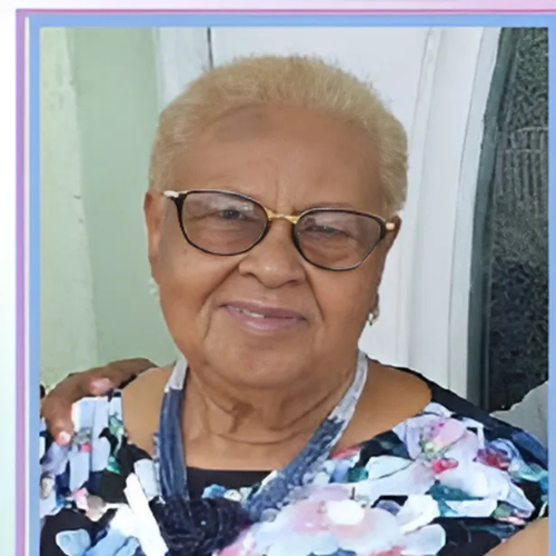 An elderly woman wearing glasses and a floral dress