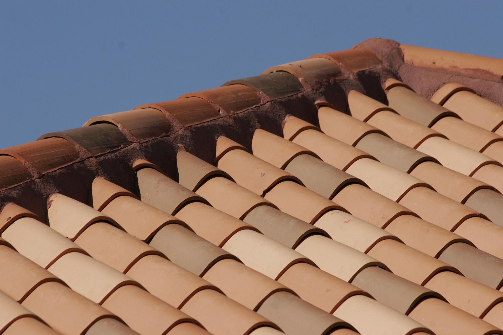 Close-up of a terracotta tile roof against a blue sky. 
