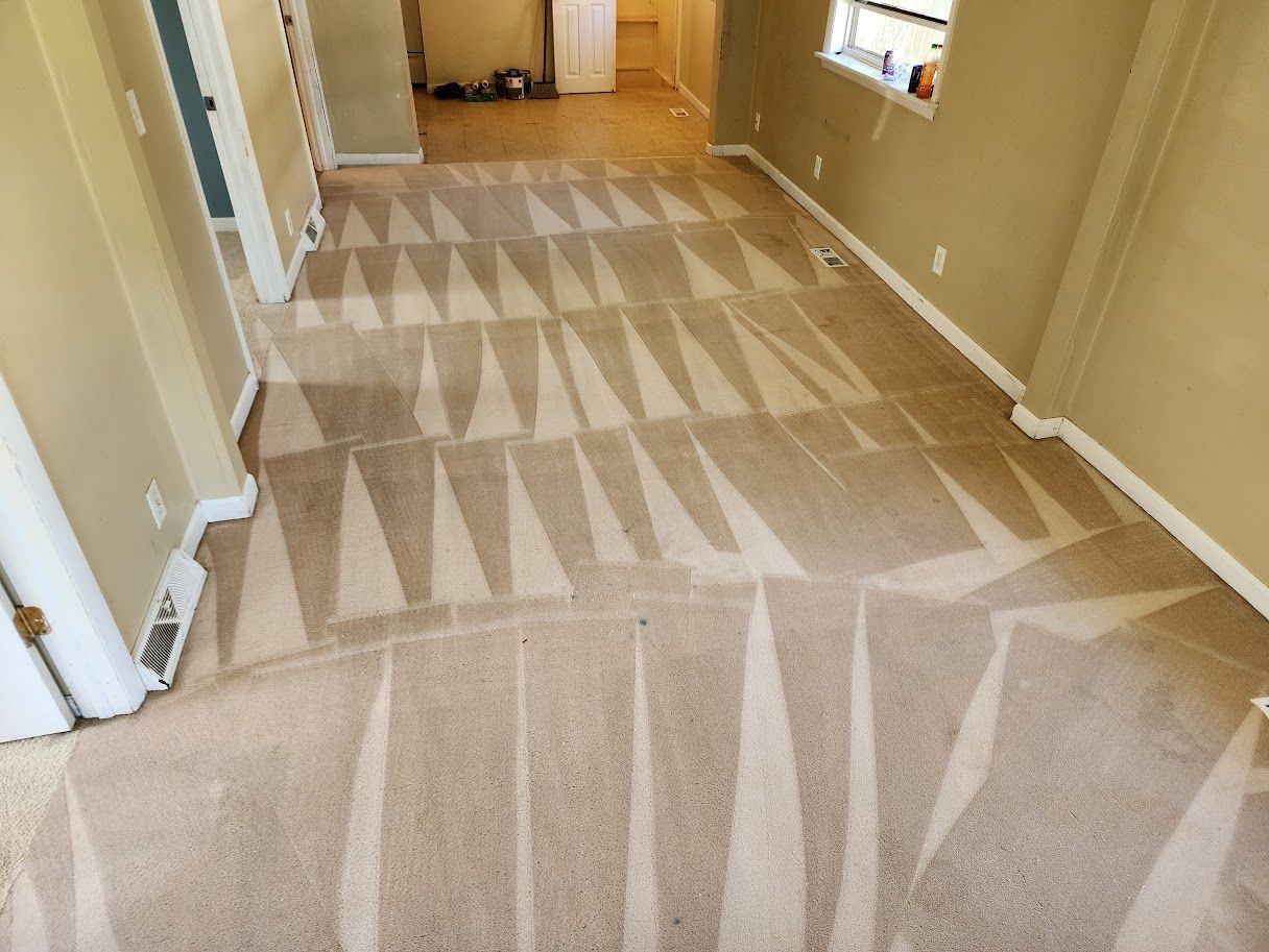 Carpeted hallway with geometric pattern and beige walls leading to a doorway