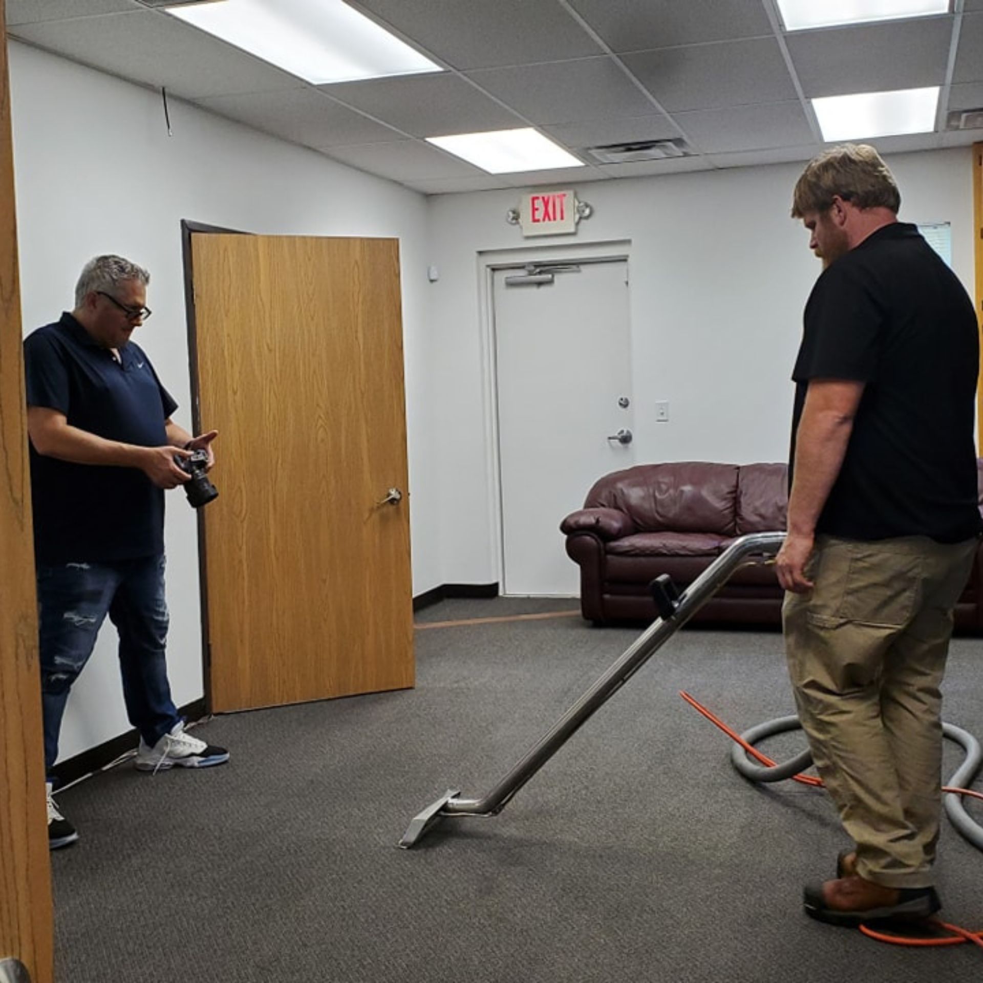 Strongarms Cleaners - Two men are standing in a room with an exit sign on the wall