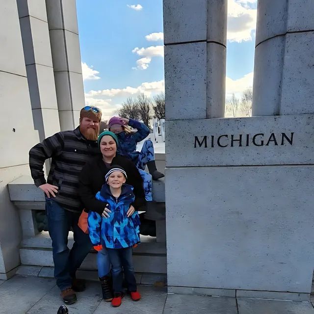 Strongarm Cleaners - A family poses in front of a michigan sign