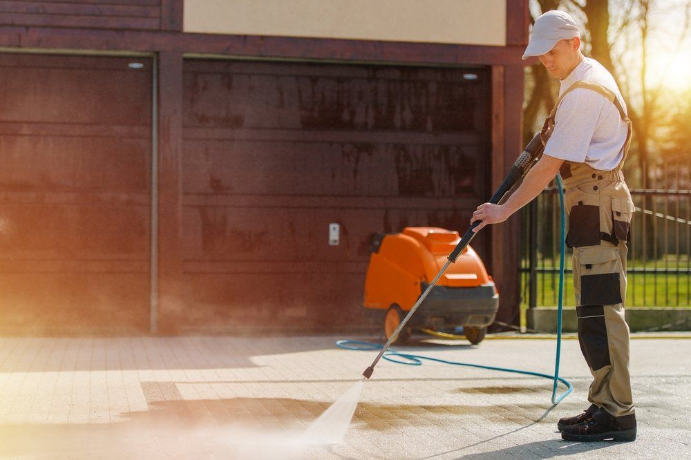 A Man Power Washing A Driveway — Pressure Cleaning in Nambucca Valley, NSW
