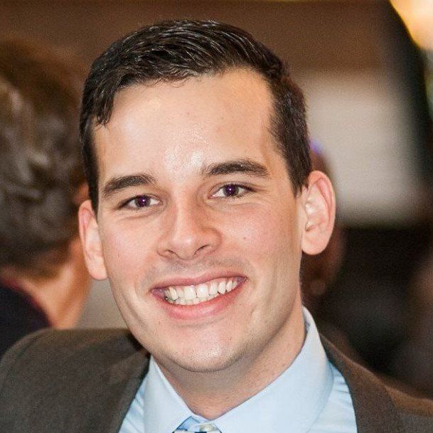 A man in a suit and tie smiles for the camera
