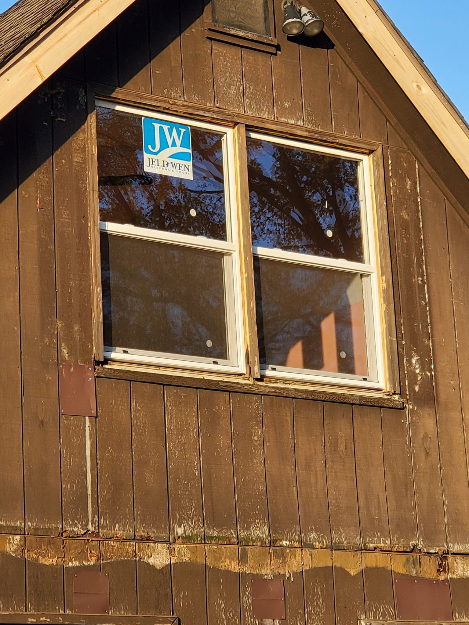 Old wooden house gable with a small four-pane window and a blue sign above it
