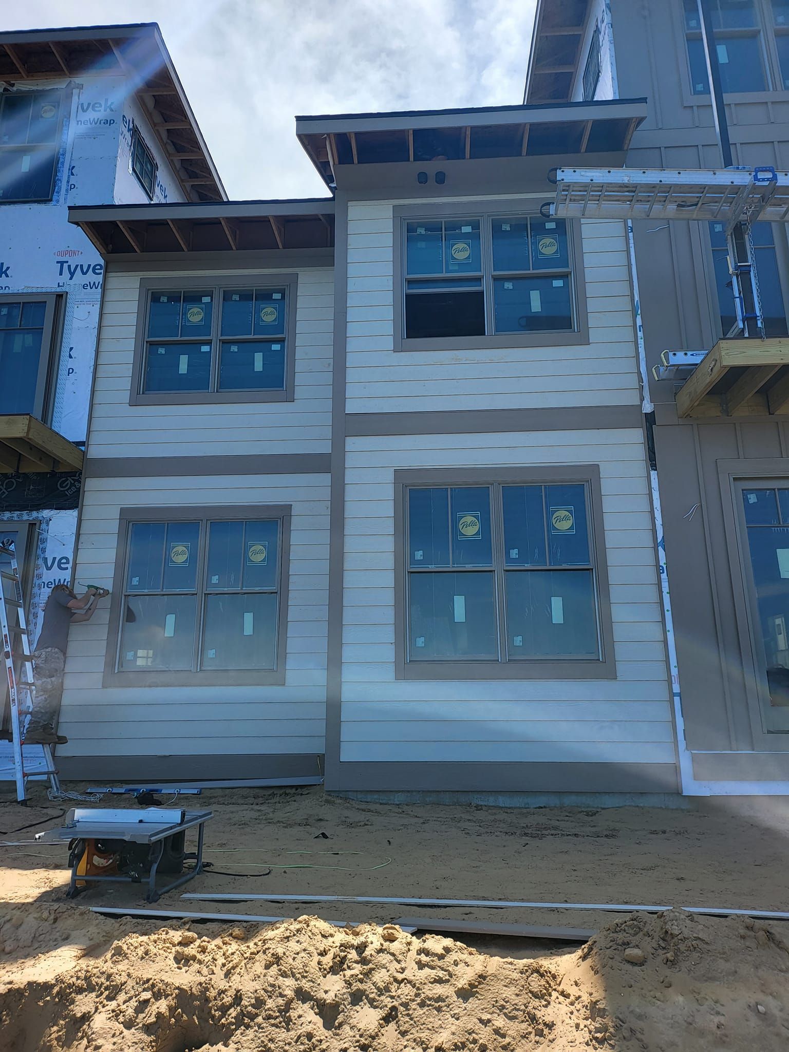Two-story house with white siding, blue window trim, and unfinished ground in front