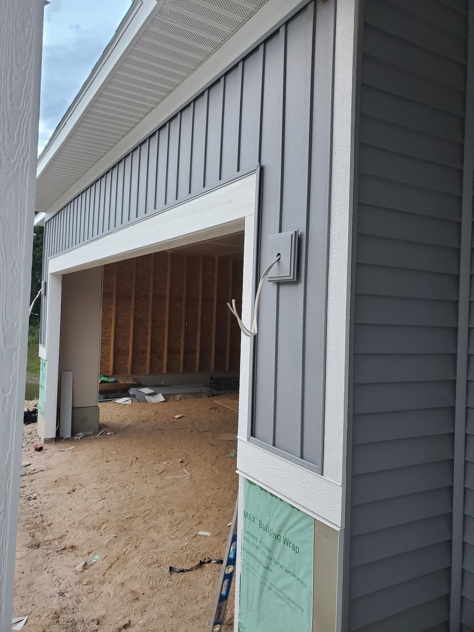 Partially built garage with gray siding, white trim, and open framing inside
