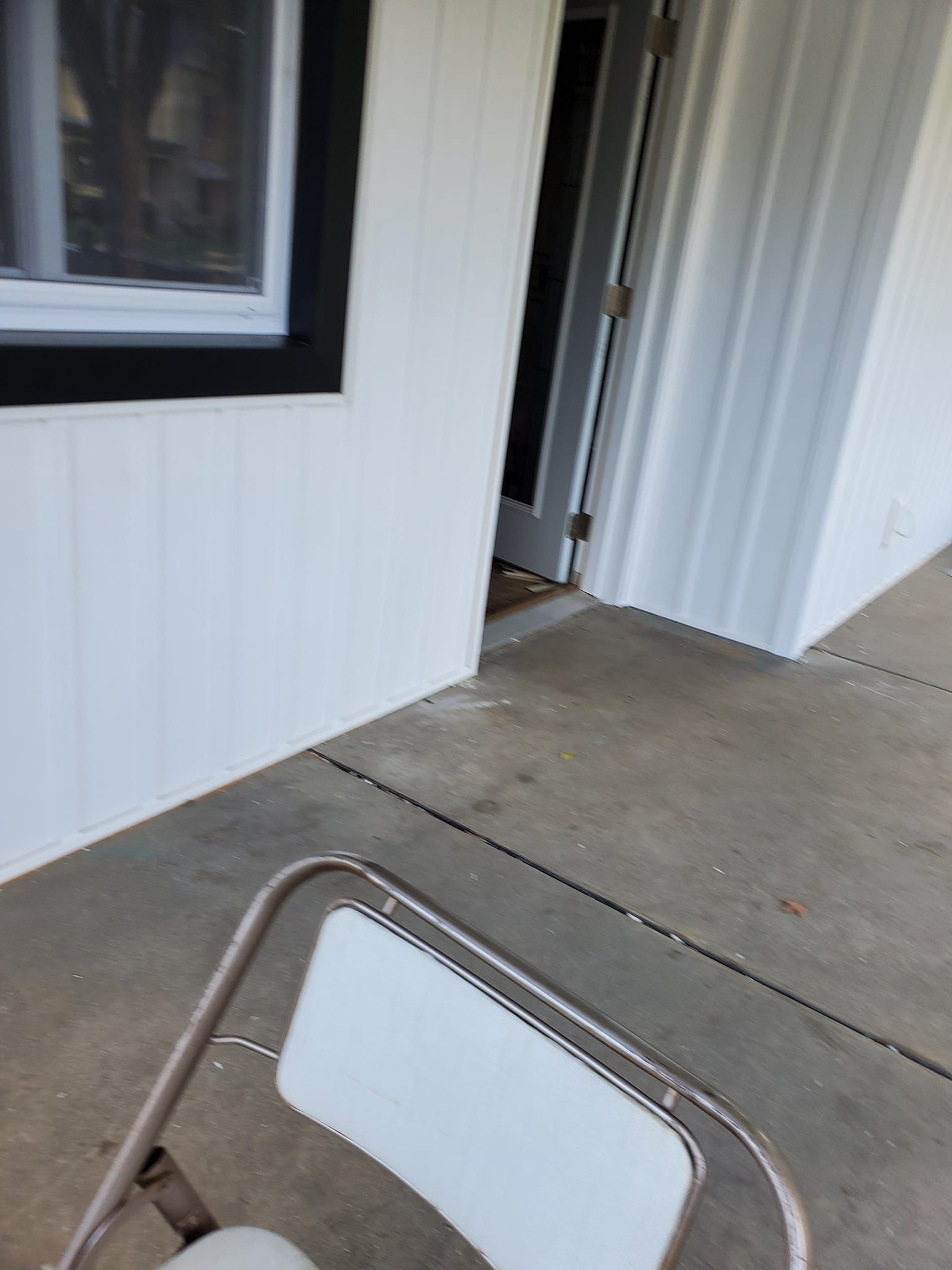 White building entrance with concrete walkway and a folding chair in the foreground