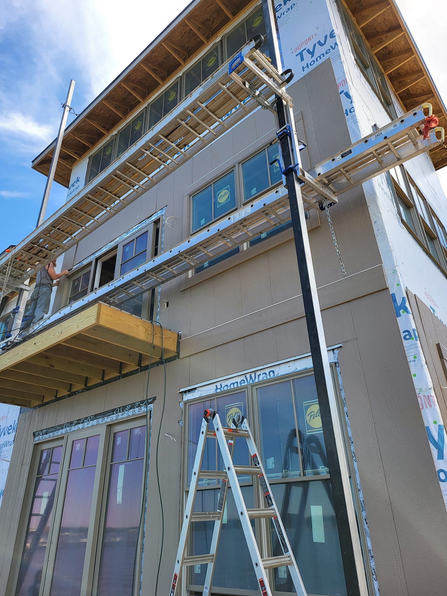 Scaffolding on a beige building with blue trim and a ladder under a clear sky