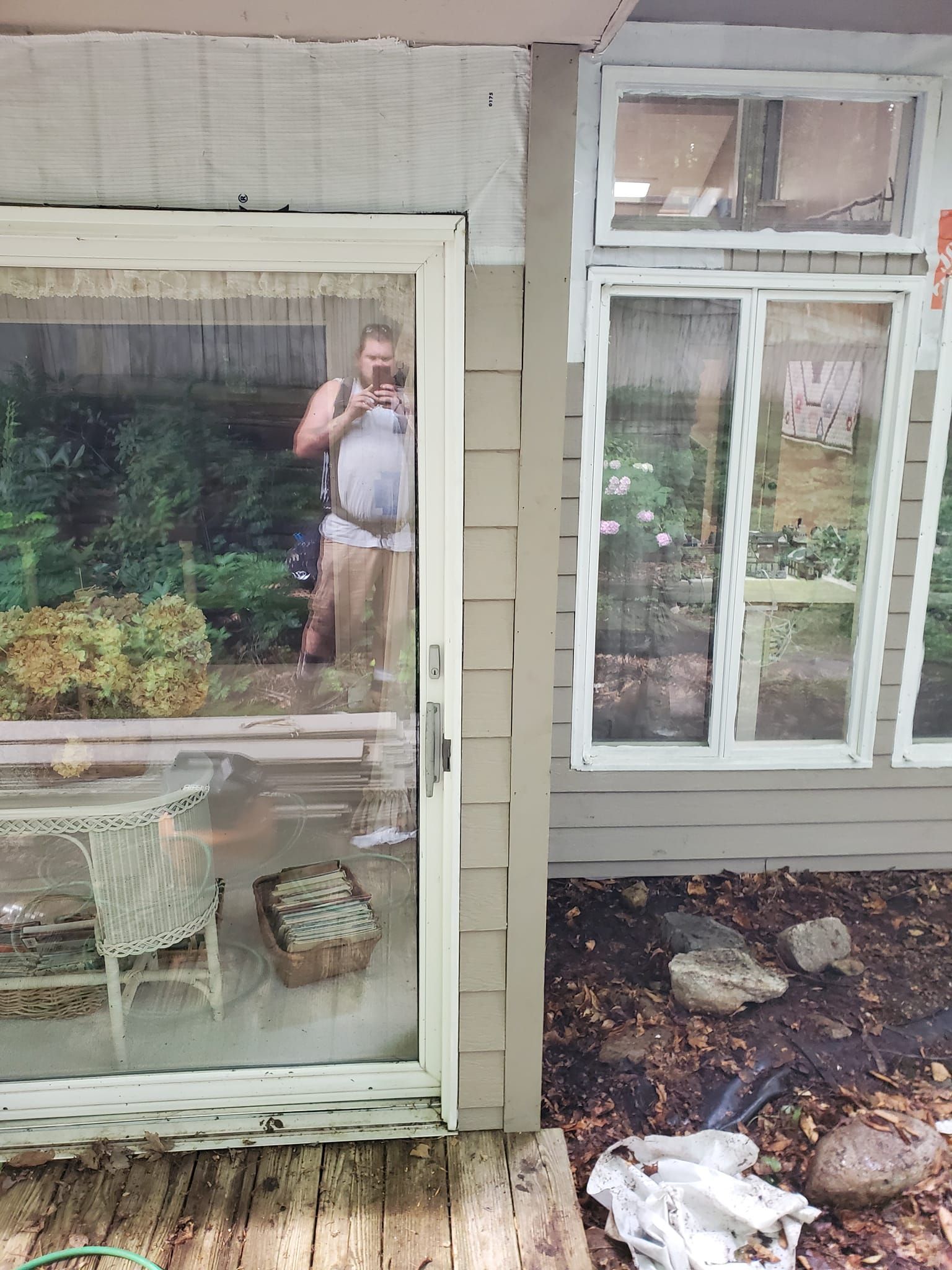 House exterior with large windows and a person taking a selfie in the left window