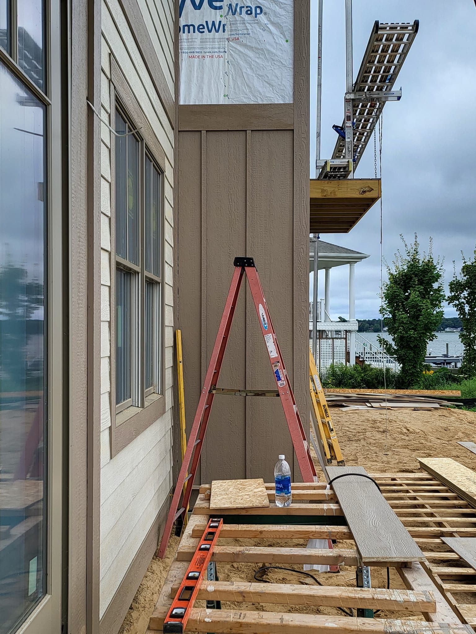 Ladder leaning against a building at a construction site, with scaffolding and walkway planks nearby.