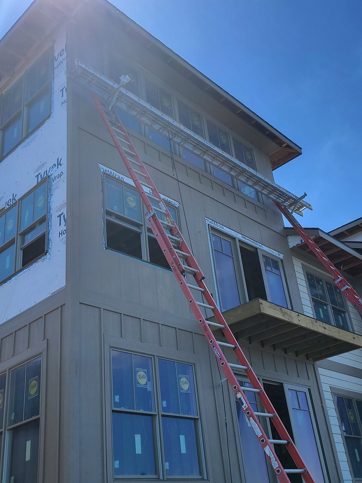 Multi-story building with red extension ladders leaning against the exterior under a blue sky