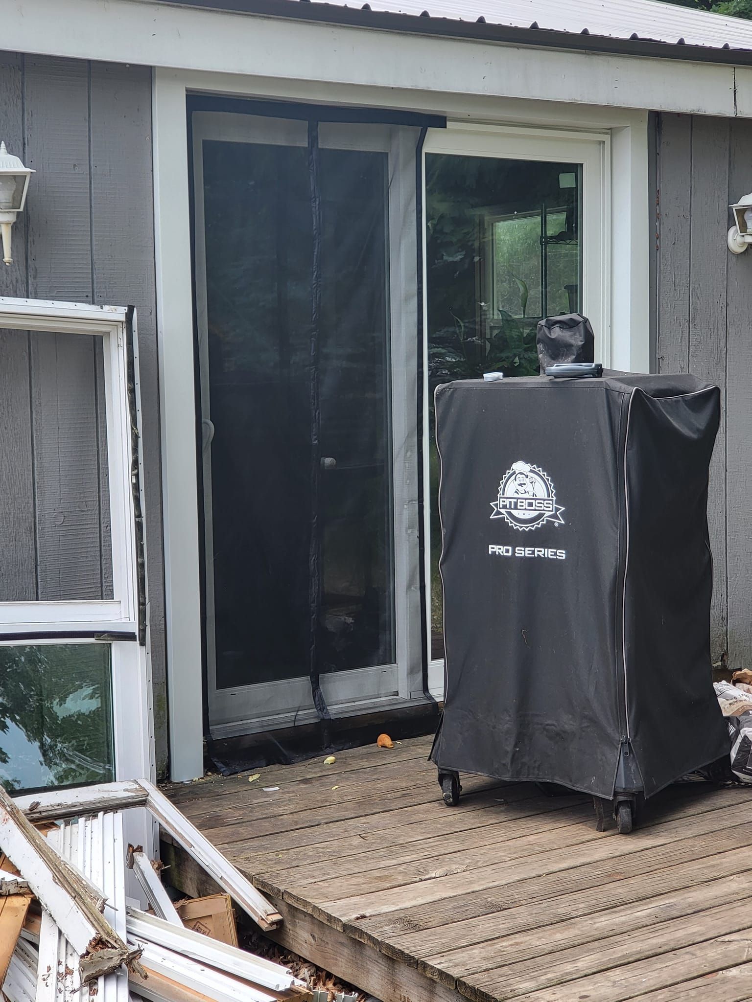 Back patio with sliding glass door and a covered grill on a wooden deck