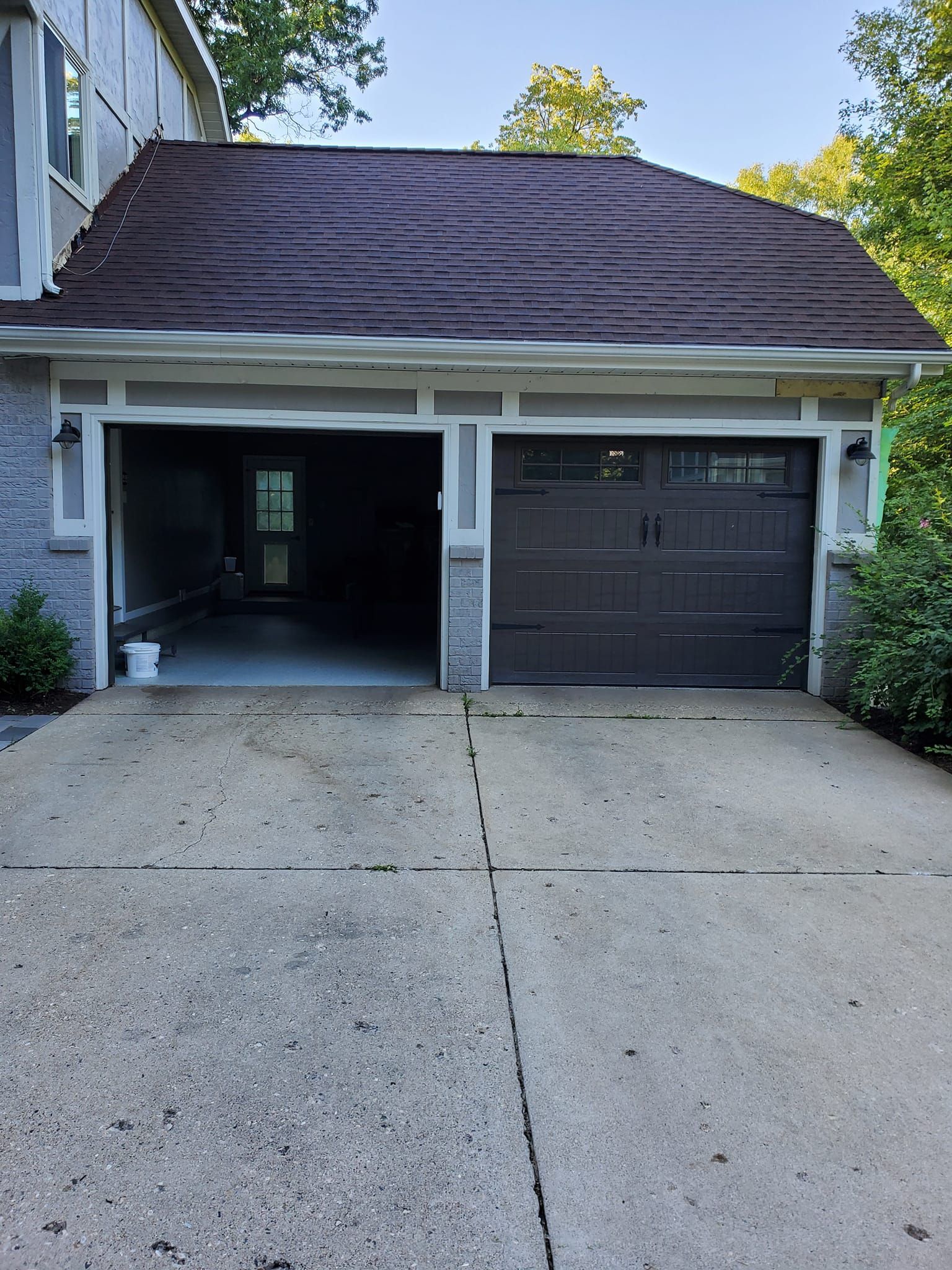 Two-car driveway with open left garage bay and closed dark garage door on a suburban house