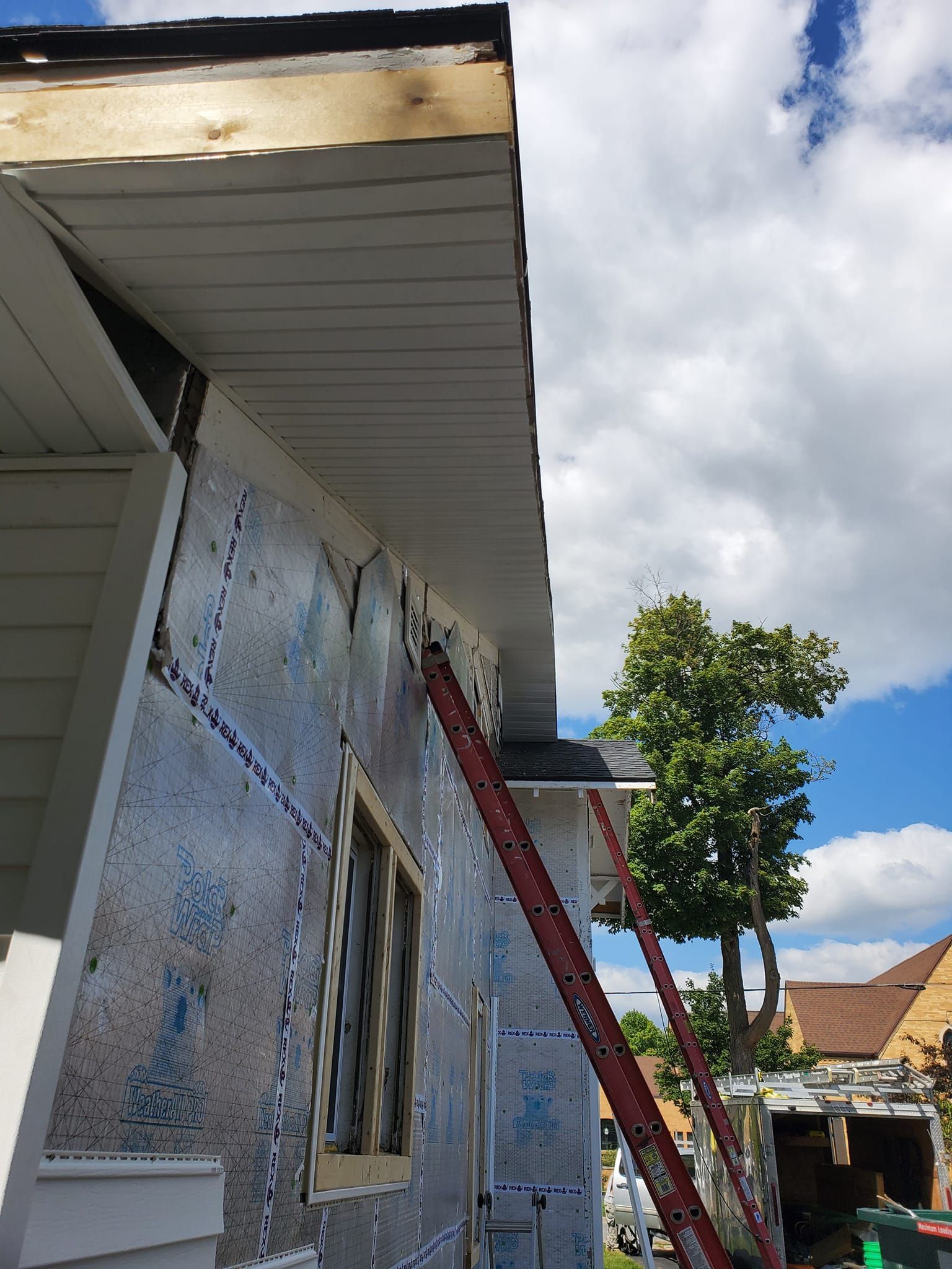 House exterior with a red ladder leaning against the wall under the roof eaves