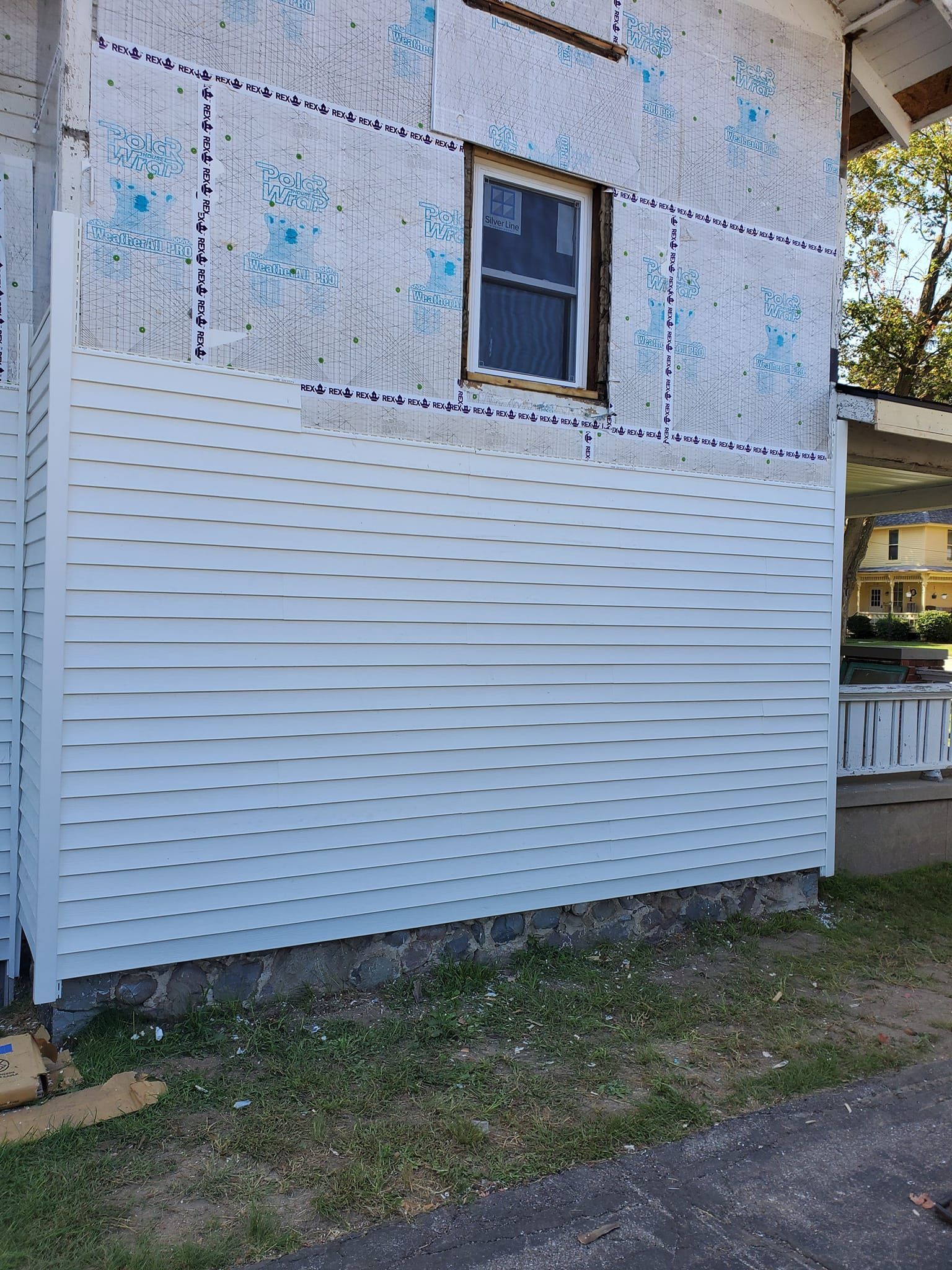 Weathered house exterior with peeling white siding, a small window, and grass along the foundation